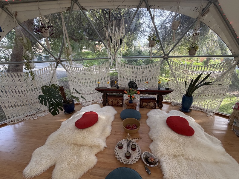 The interior of the Aum Dome with altar, macrame, and sheepskins